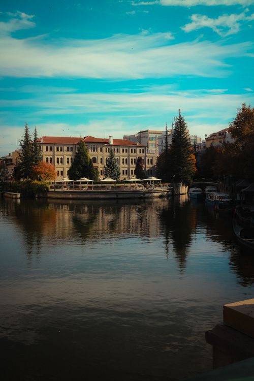 Free Picturesque canal reflecting historic architecture under a bright blue sky. Stock Photo