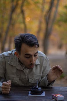 A young man blows out a candle on a cupcake outdoors in autumn, Balıkesir, Türkiye.