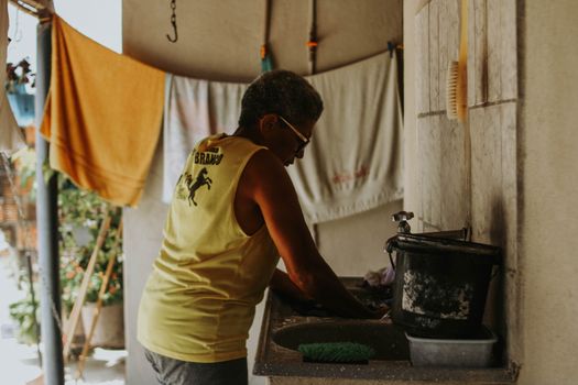 Senior man washing clothes by hand in an outdoor setting.