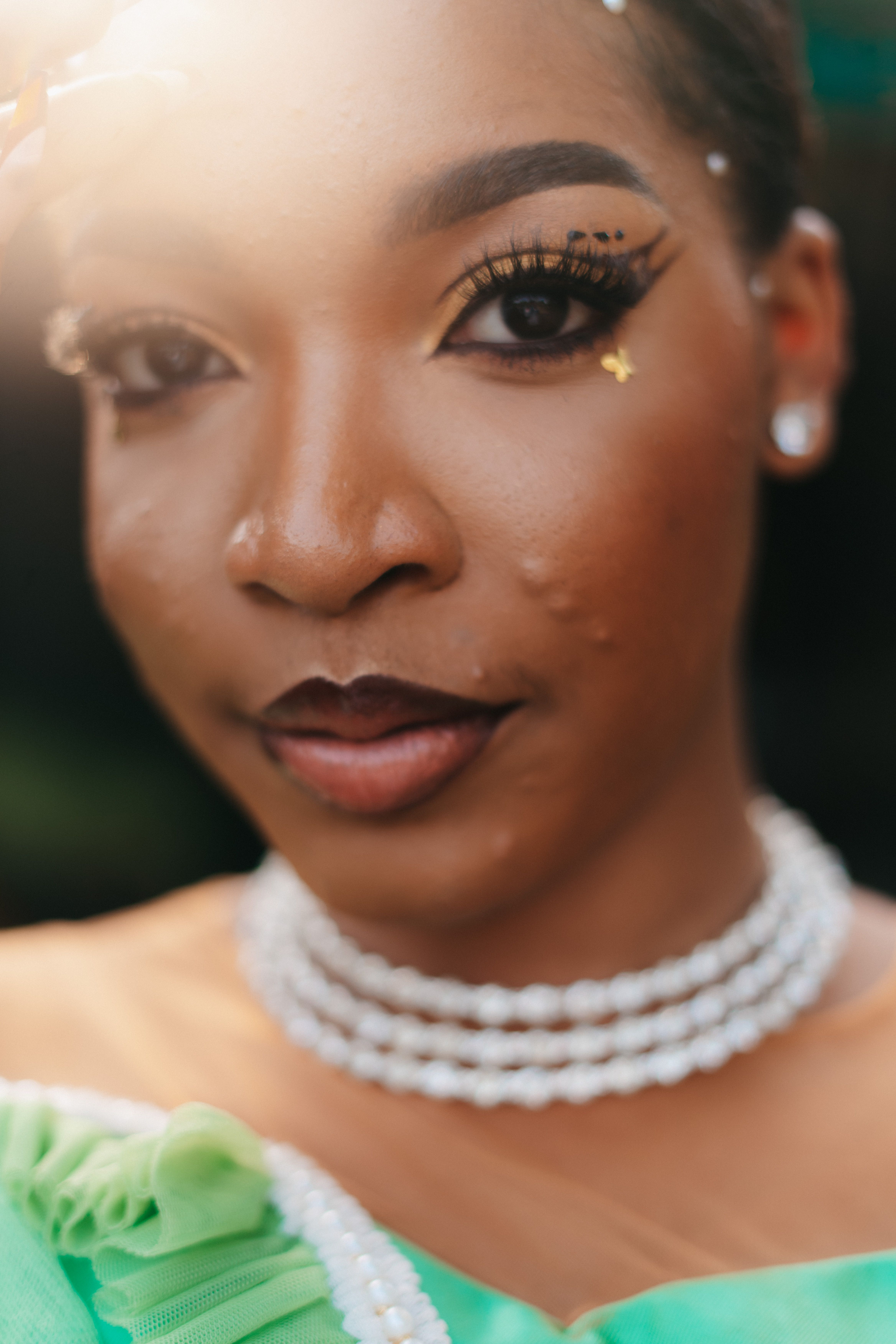 Captivating close-up portrait of a stylish Nigerian woman with intricate makeup and jewelry, exuding elegance.