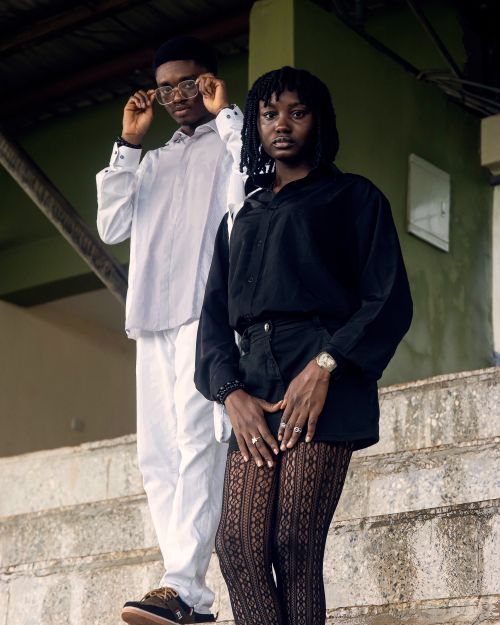 Free Fashionable young adults in contrasting outfits posing confidently on a staircase. Stock Photo