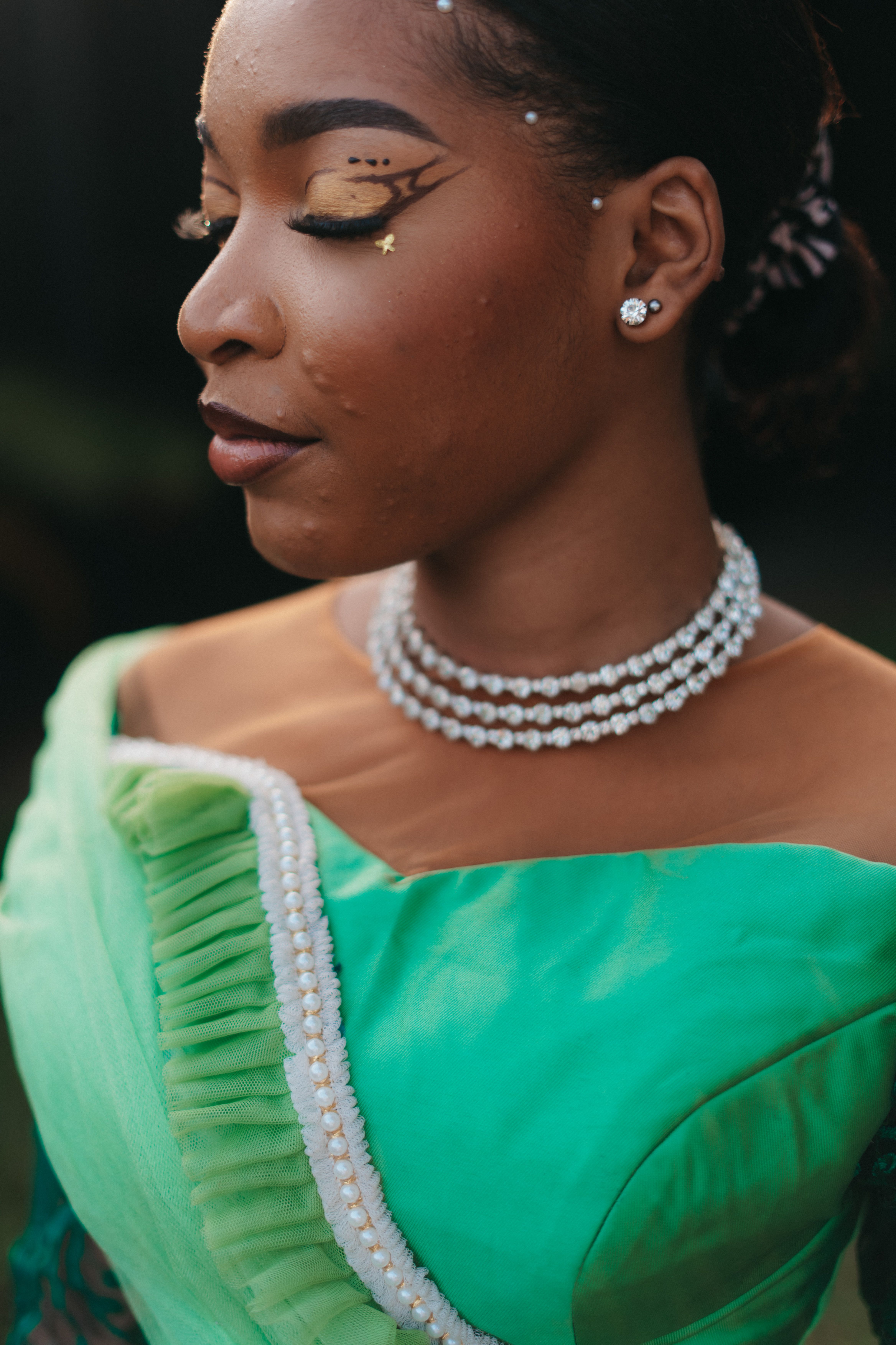 Close-up portrait of a Nigerian bride in elegant bridal attire with artistic makeup.