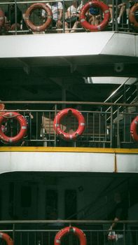 A ferry with visible life buoys and passengers enjoying the trip.