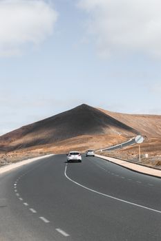A serene drive through Lanzarote's arid landscape, featuring a winding mountain road under a clear sky.
