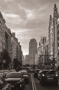 Black and white view of Gran Vía, Madrid with traffic and iconic buildings.