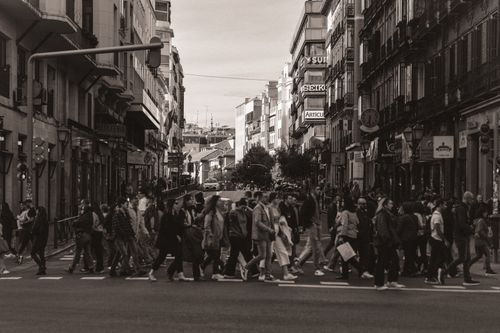 Free A bustling city street in Madrid with people crossing. Urban lifestyle captured in sepia tones. Stock Photo