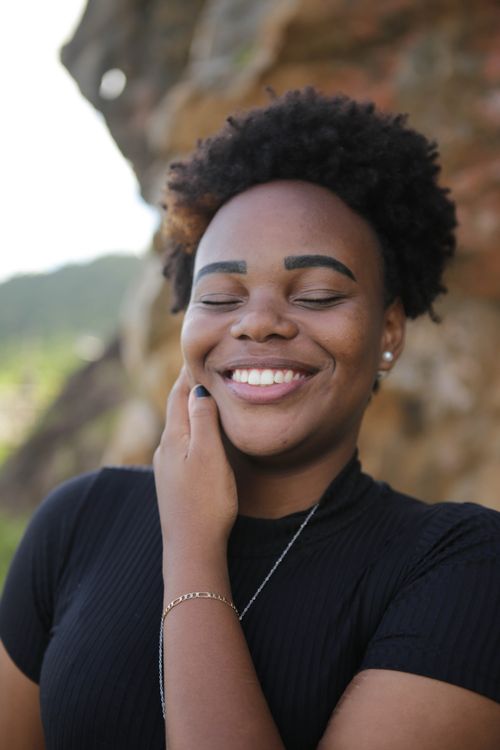 Free Portrait of a woman smiling with joy in an outdoor setting, creating a warm and happy mood. Stock Photo