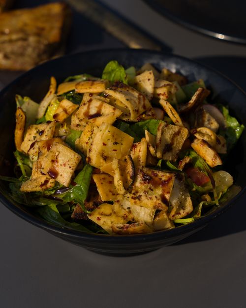 Free A vibrant and healthy Middle Eastern fattoush salad with crispy pita and fresh greens served in a black bowl. Stock Photo