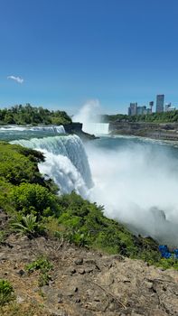 Stunning summer view of Niagara Falls with clear blue skies and cityscape.