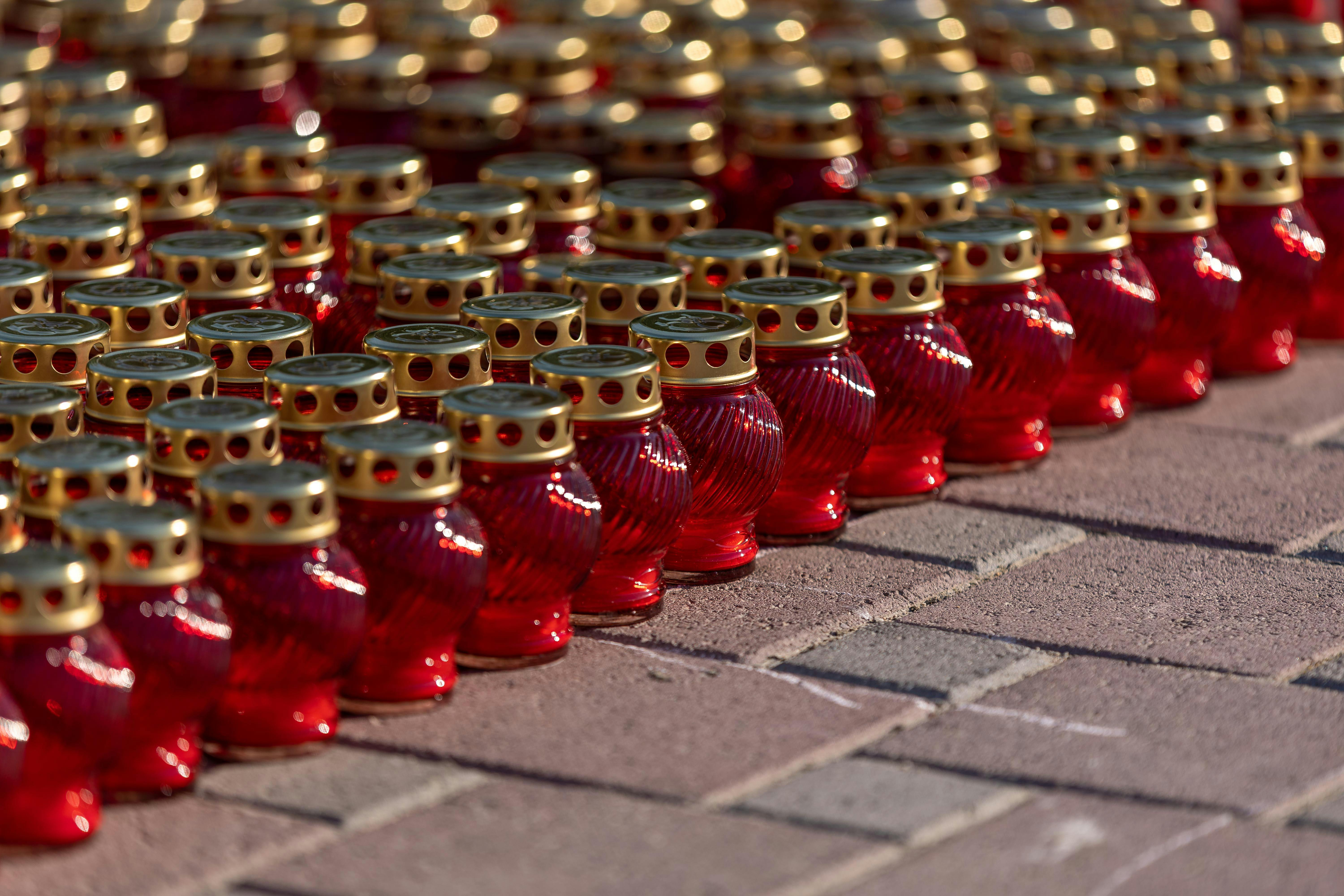 Rows of red candle lanterns with gold tops arranged outdoors for an event.