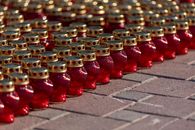 Rows of red candle lanterns with gold tops arranged outdoors for an event.