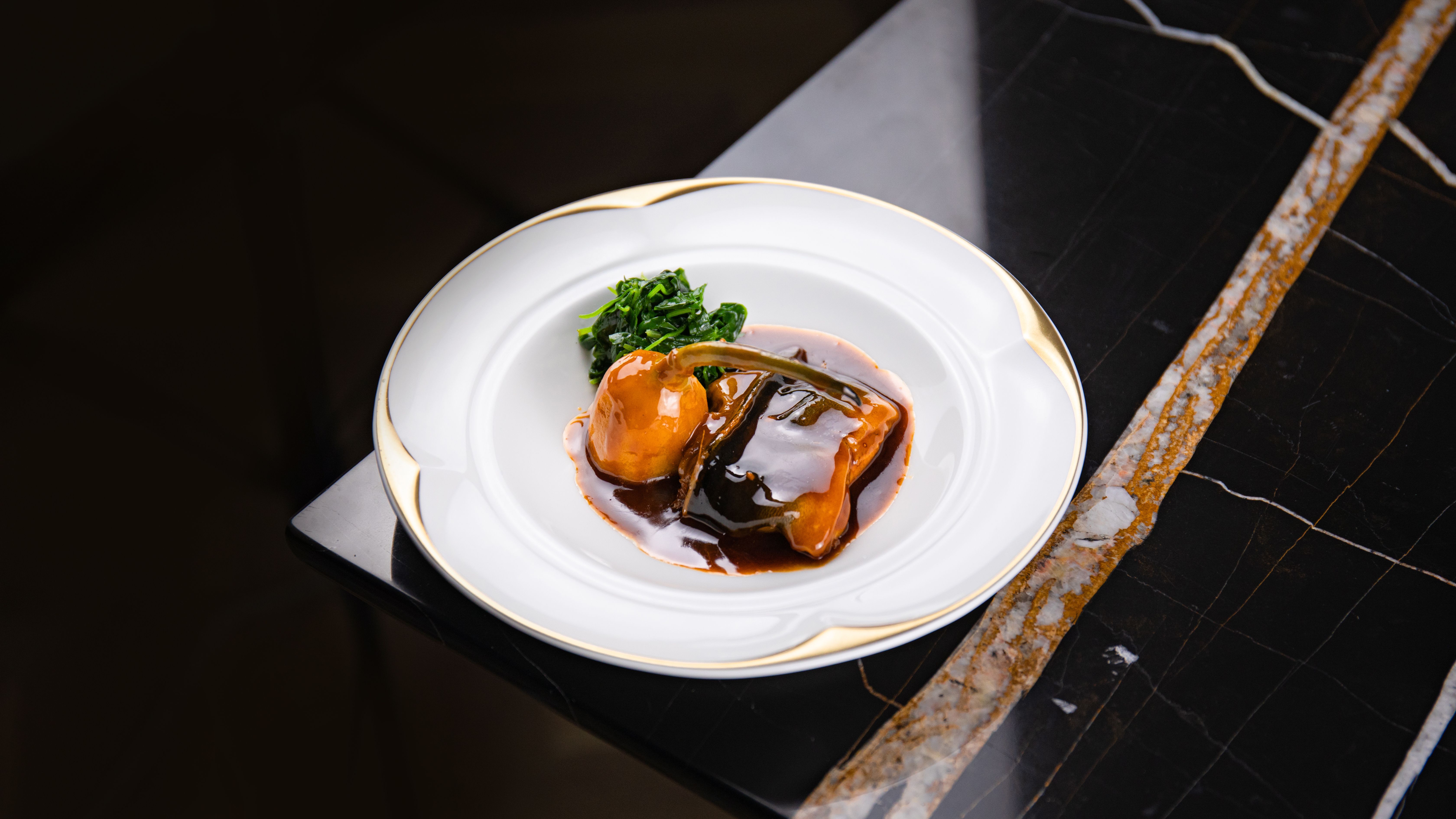 Prato gourmet elegantemente disposto em mesa de mármore, simbolizando a excelência gastronômica do Le Bristol Paris.