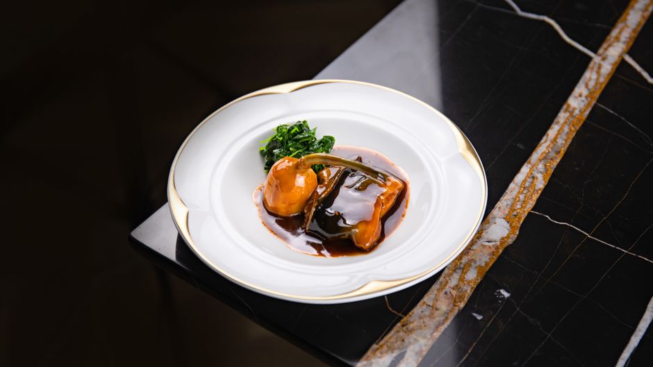 Prato gourmet elegantemente disposto em mesa de mármore, simbolizando a excelência gastronômica do Le Bristol Paris.