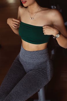 Stylish woman wearing a green top and gray leggings, showcasing fitness and fashion.