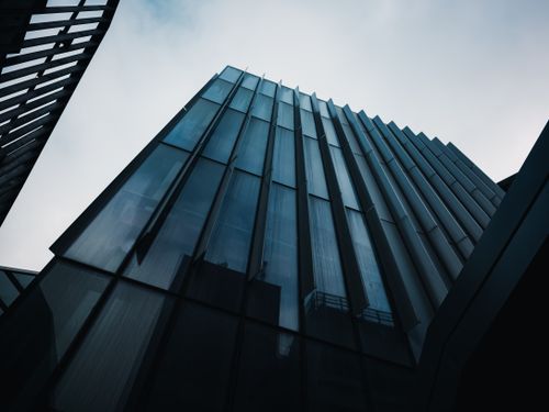 Free Low angle view of a modern glass skyscraper under a cloudy sky. Stock Photo