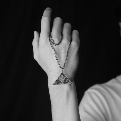 Free Close-up of a hand holding a triangular pendant in black and white. Stock Photo