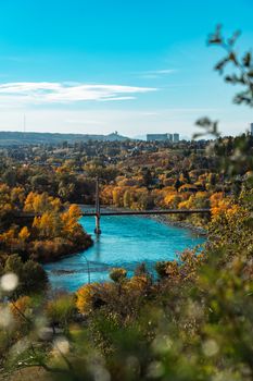 Vibrant autumn landscape of Calgary's Bow River with colorful foliage and clear blue skies.