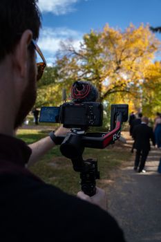 A videographer captures an autumn wedding scene with vibrant foliage in Calgary, Canada.