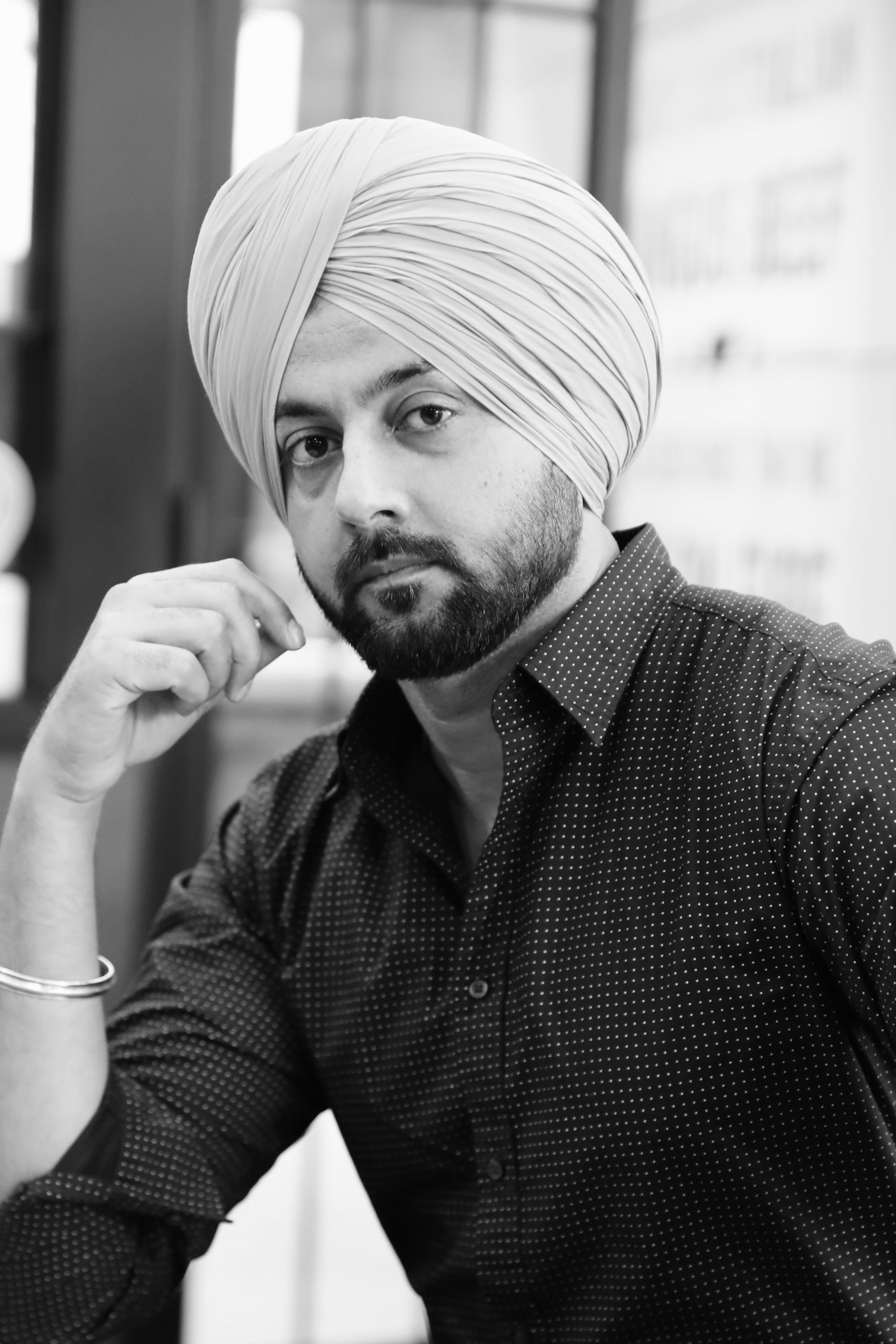 Elegant black and white portrait of an adult man wearing a turban indoors.