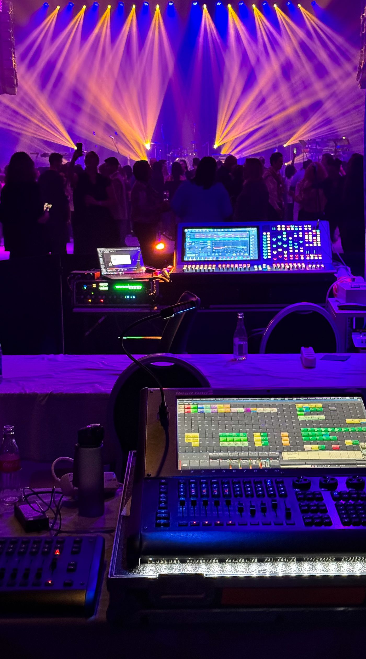 Mesa de control de sonido e iluminación con el público al fondo durante un evento