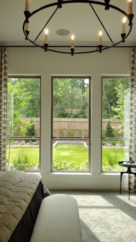 Modern bedroom interior with large windows revealing a lush garden view.