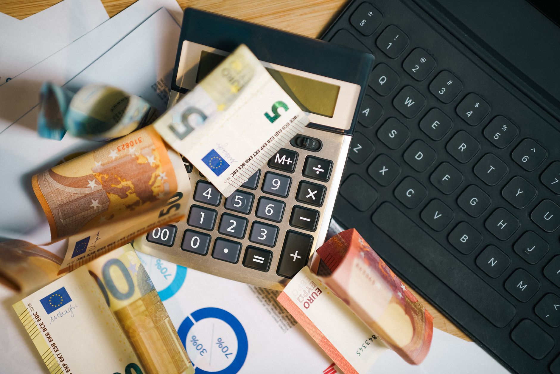 Hollanda'da modern bir ofis ortamında bilgisayar başında çalışan bir dijital pazarlama uzmanı ve Euro para birimini temsil eden finansal grafikler.