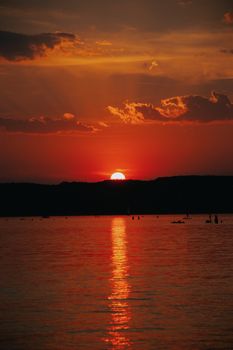 Dramatic sunset with vibrant hues reflecting over a peaceful lake in Hungary, capturing nature's beauty.
