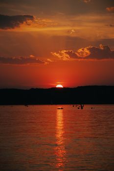 Enjoy a breathtaking view of the sun setting over a tranquil lake in Hungary, with a reflection on the water surface.