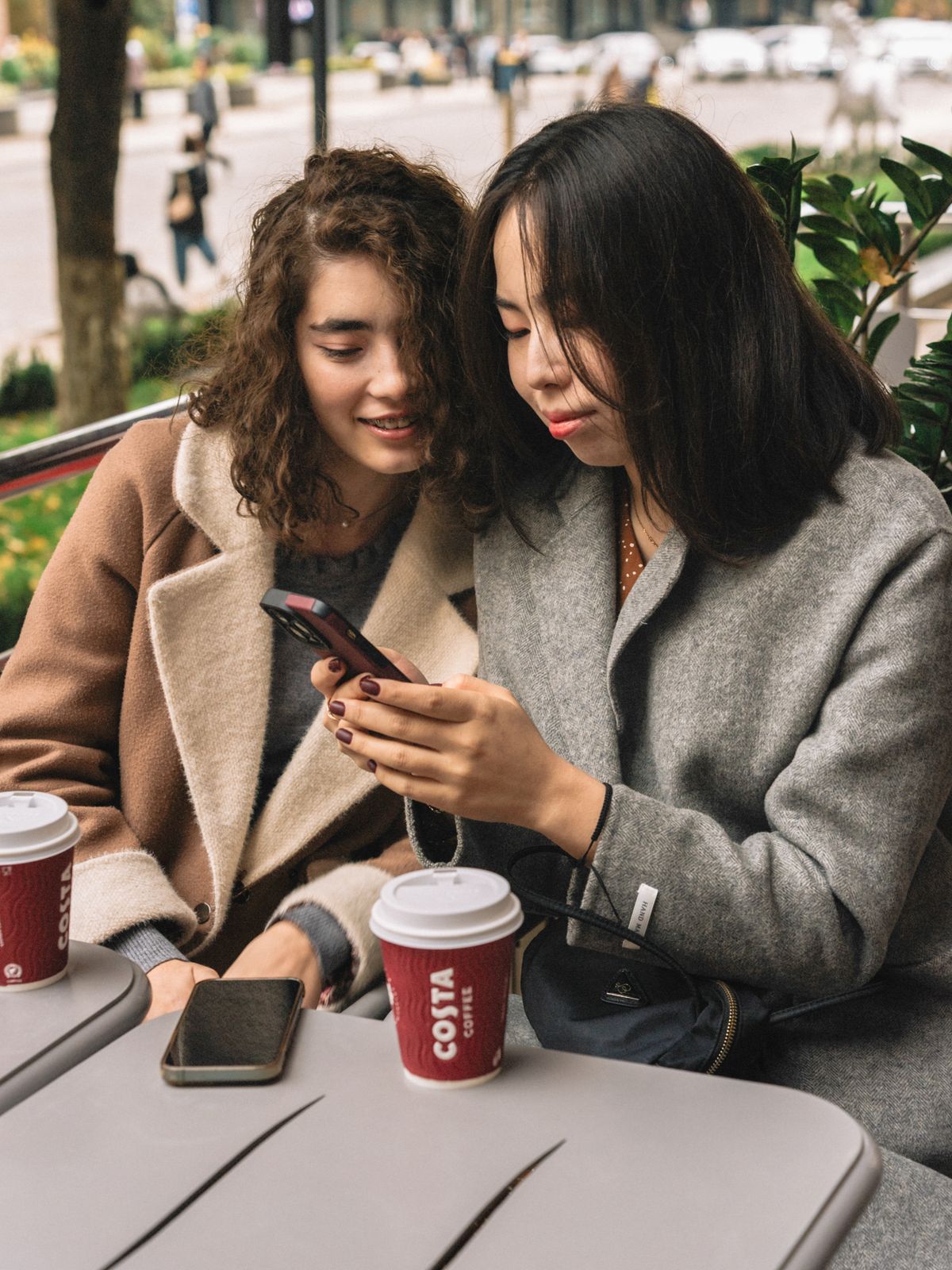 Two friends talking together over coffee outdoors