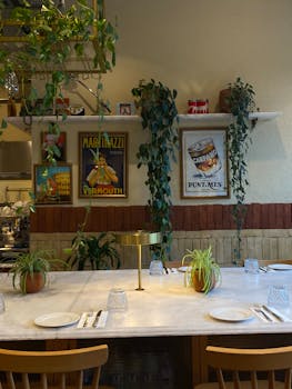 Warm restaurant setting with vintage posters and hanging plants.