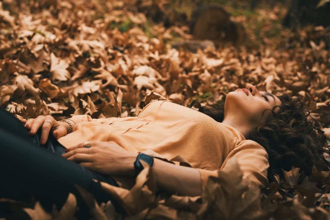 Woman Lying on Autumn Leaves in Tranquil Forest · Free Stock Photo