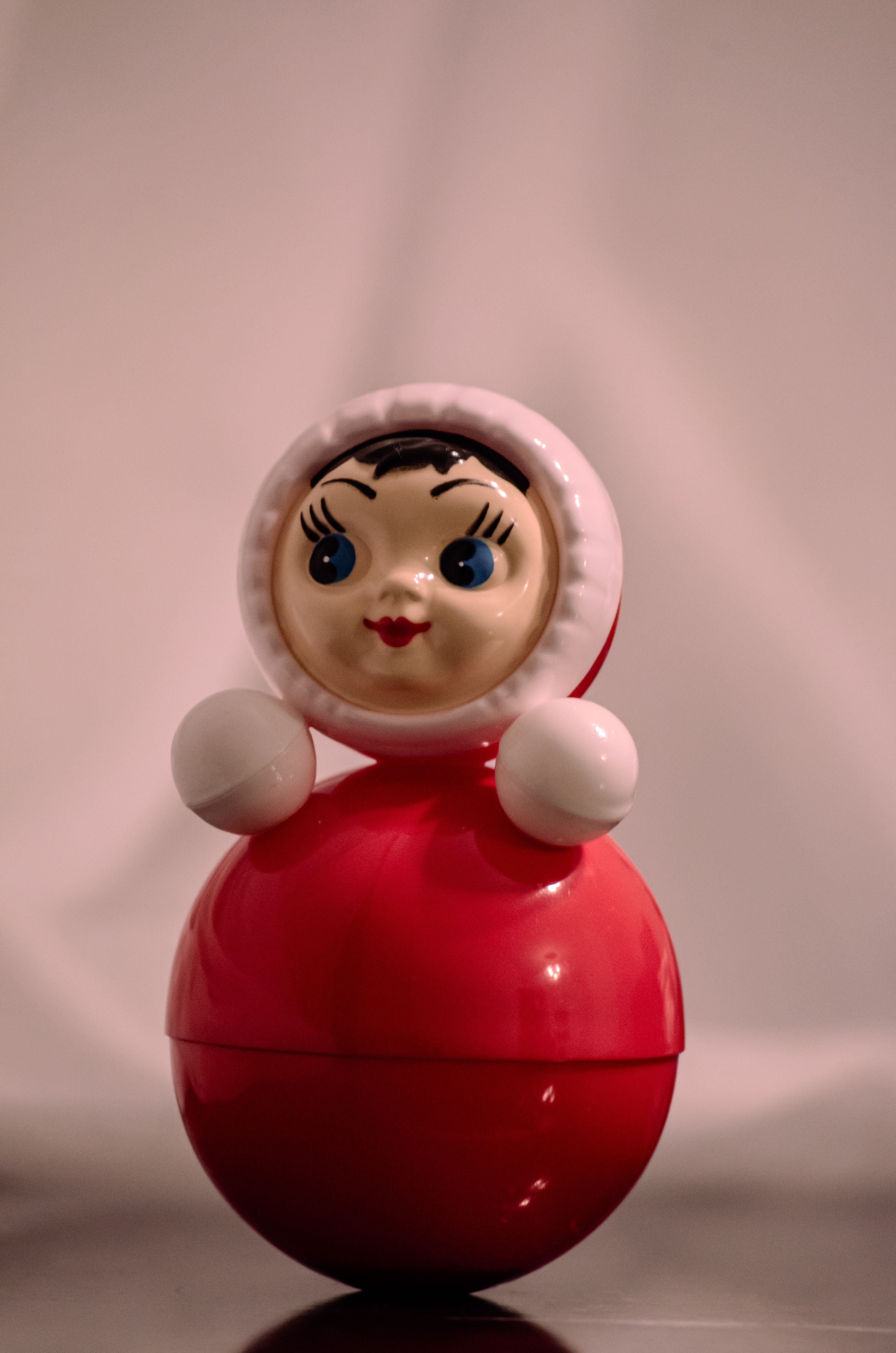 Close-up of a classic red and white roly-poly toy with a smiling face, indoors.