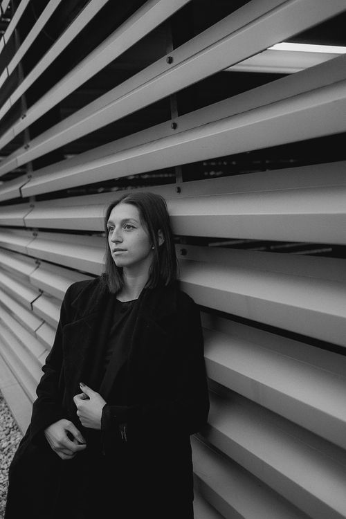Free Stylish black and white portrait of a woman leaning against a modern architectural wall. Stock Photo