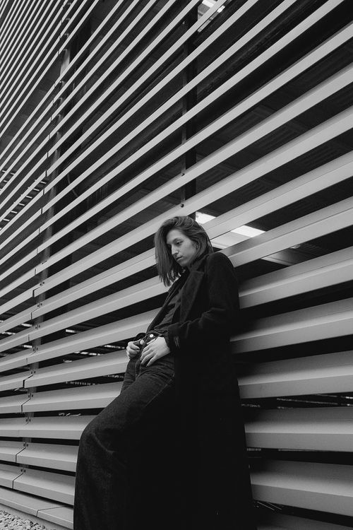 Free Stylish woman leaning against modern architecture in black and white. Artistic urban portrait. Stock Photo