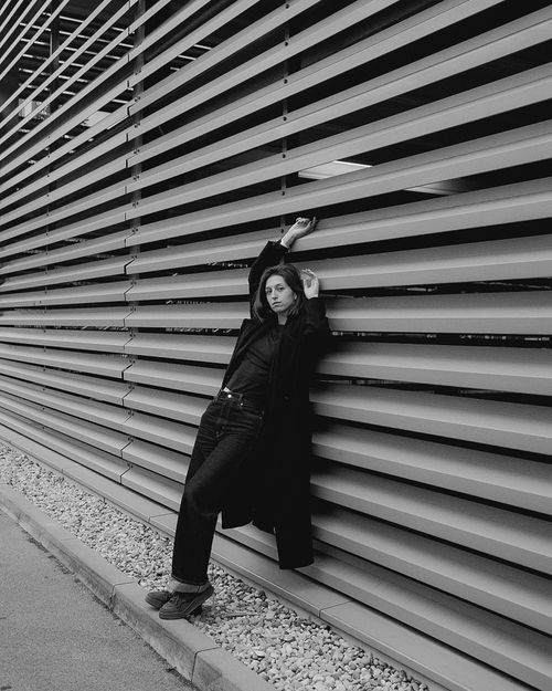 Free Black and white portrait of a person leaning against a modern slatted wall, capturing a moody urban aesthetic. Stock Photo