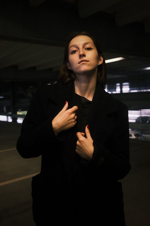 Free Moody portrait of a woman in a dimly lit urban parking garage, evoking a mysterious ambiance. Stock Photo