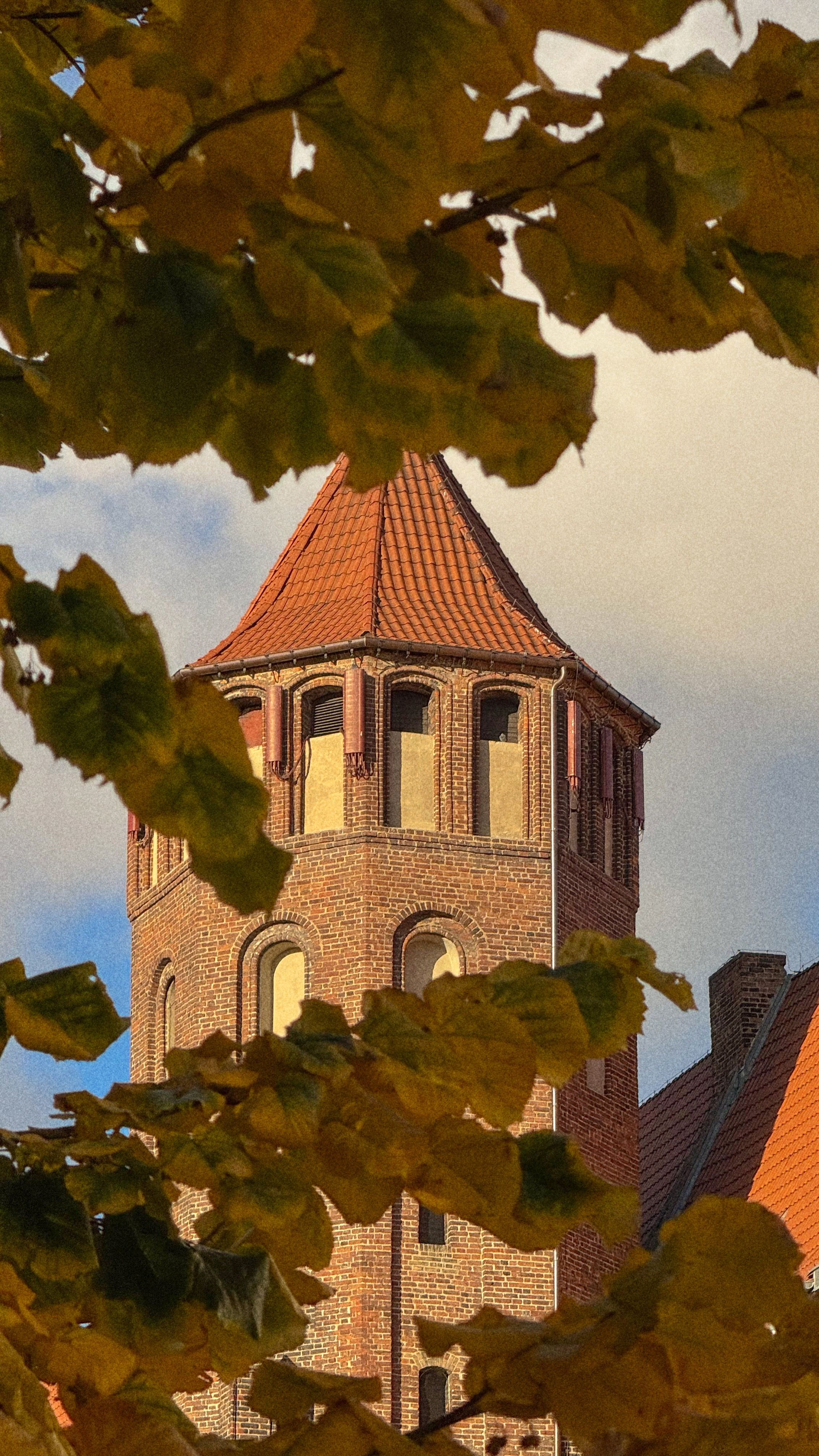 Historic brick tower framed by fall foliage, showcasing medieval architecture.