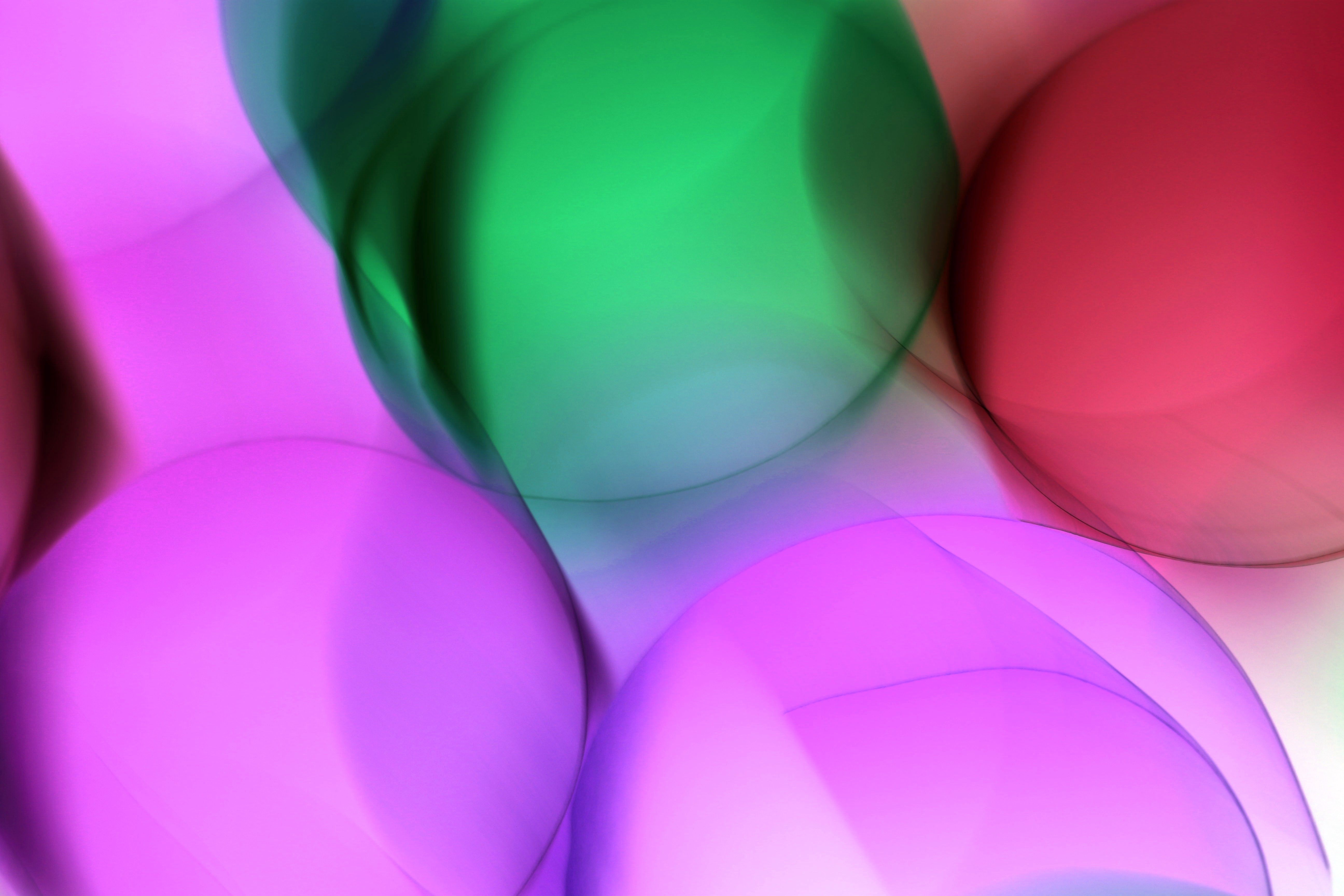 A vibrant abstract bokeh image with overlapping circles in vivid pink, green, and red hues.