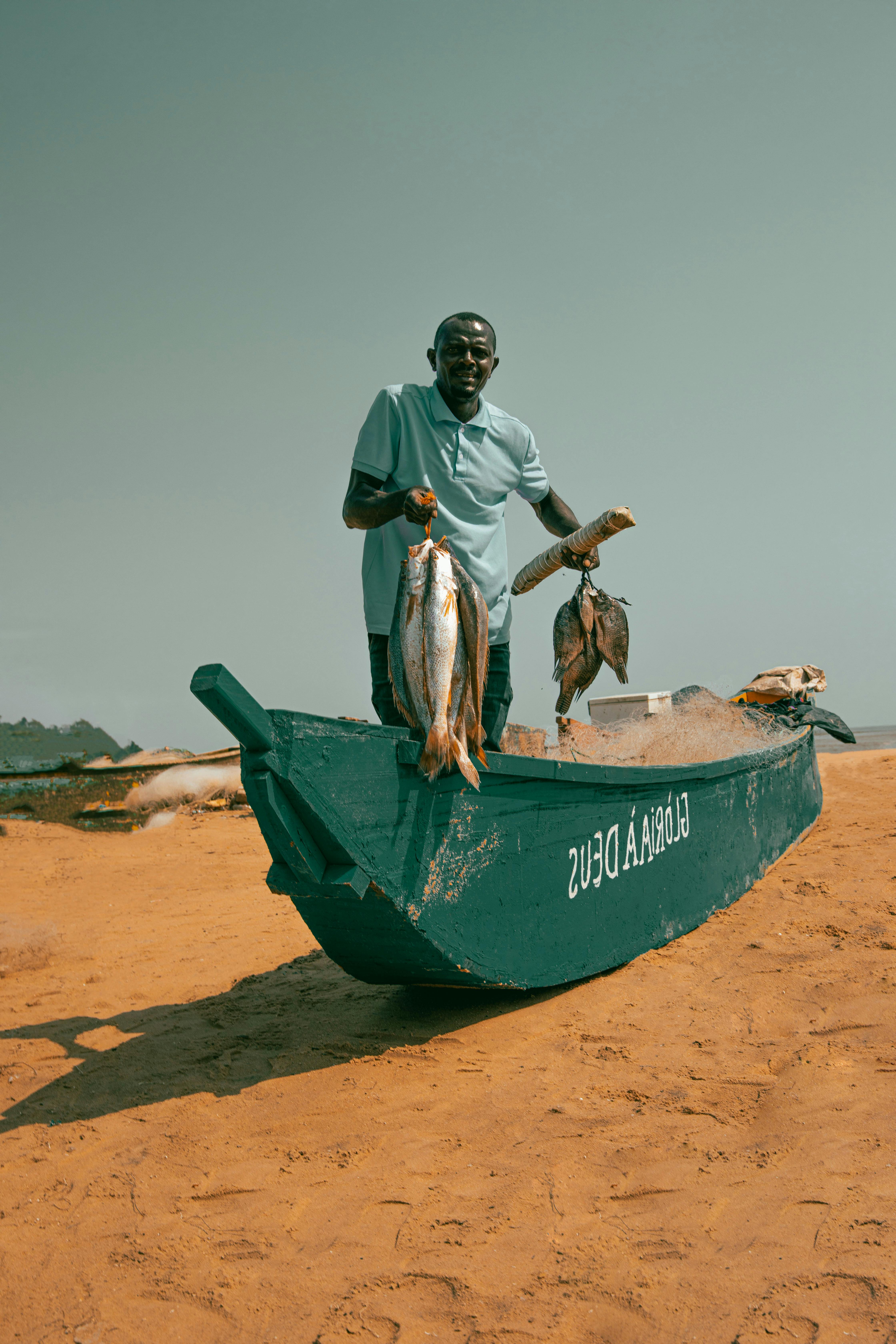 A fisherman proudly displays his catch on a sandy beach in Cabinda, Angola.