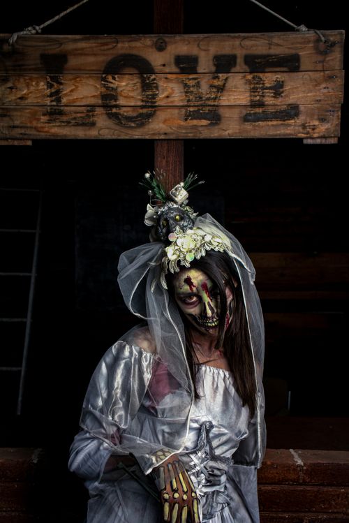 Free Zombie bride in tattered gown under a love sign, perfect for Halloween themes. Stock Photo