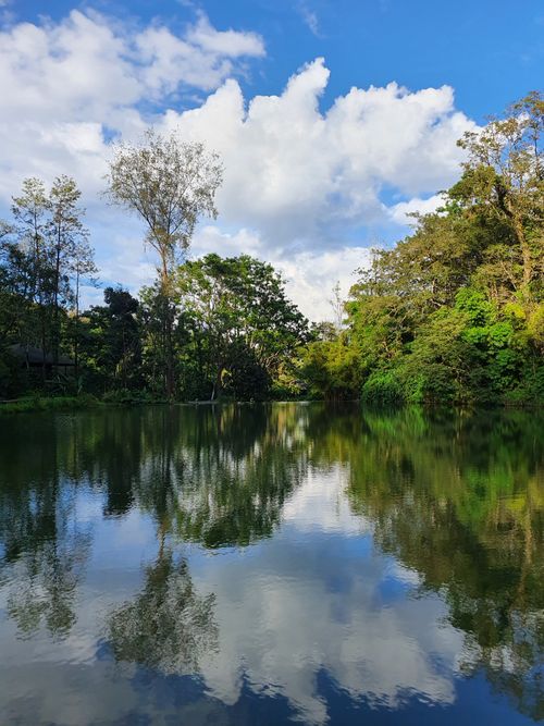 Free Serene lake with lush greenery reflecting the sky in Madikeri, India. Stock Photo