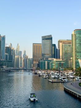 Scenic view of Dubai Marina's modern skyscrapers and luxury yachts at day, showcasing urban architecture.