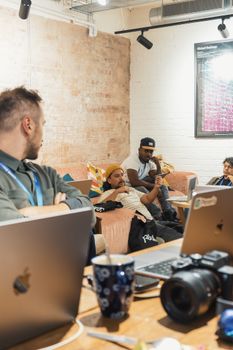 Team having an informal discussion with laptops and coffee in a modern office setting.
