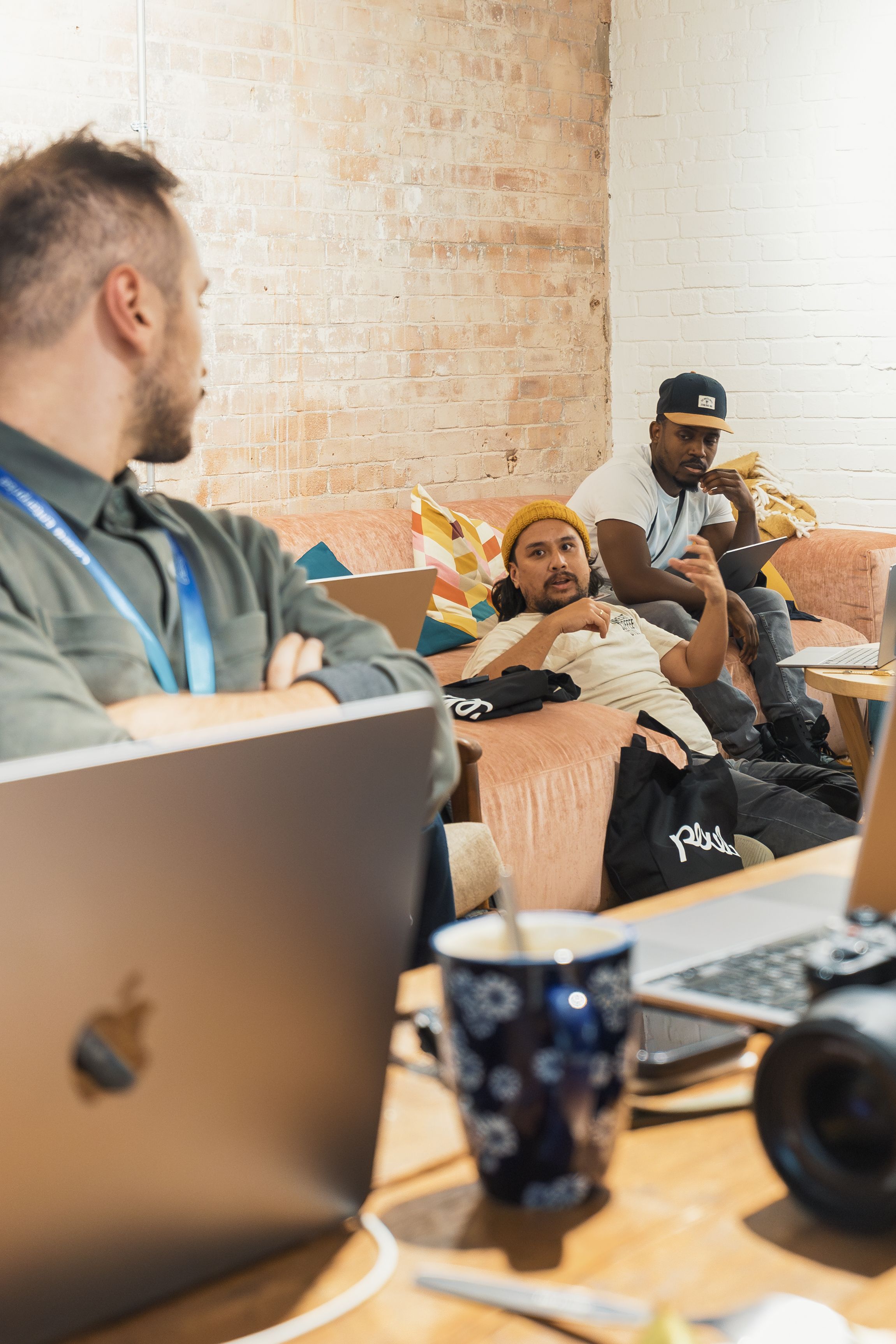 A relaxed team meeting in a stylish office lounge with laptops and casual discussion.