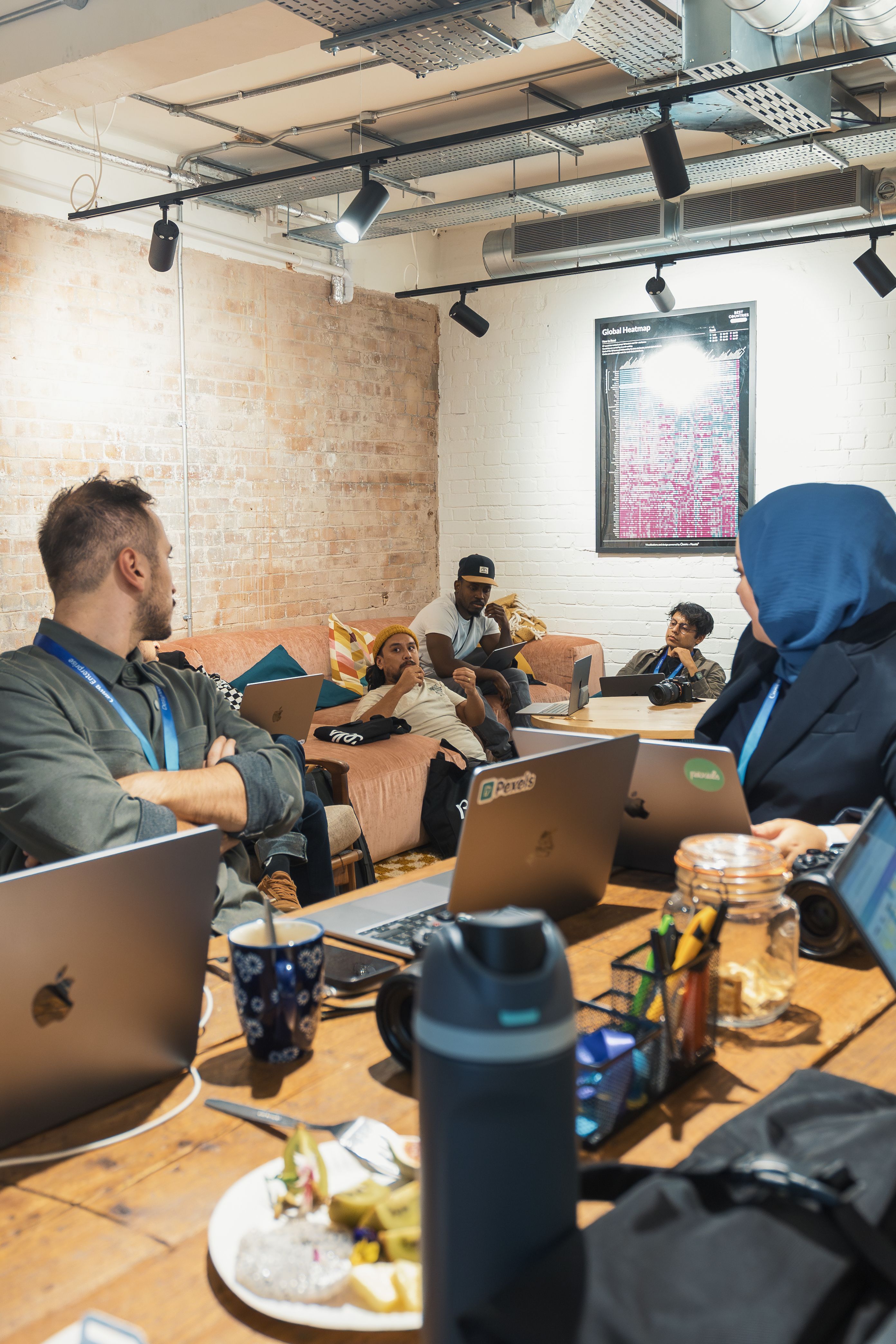 A relaxed office meeting with young adults discussing around a table with laptops.