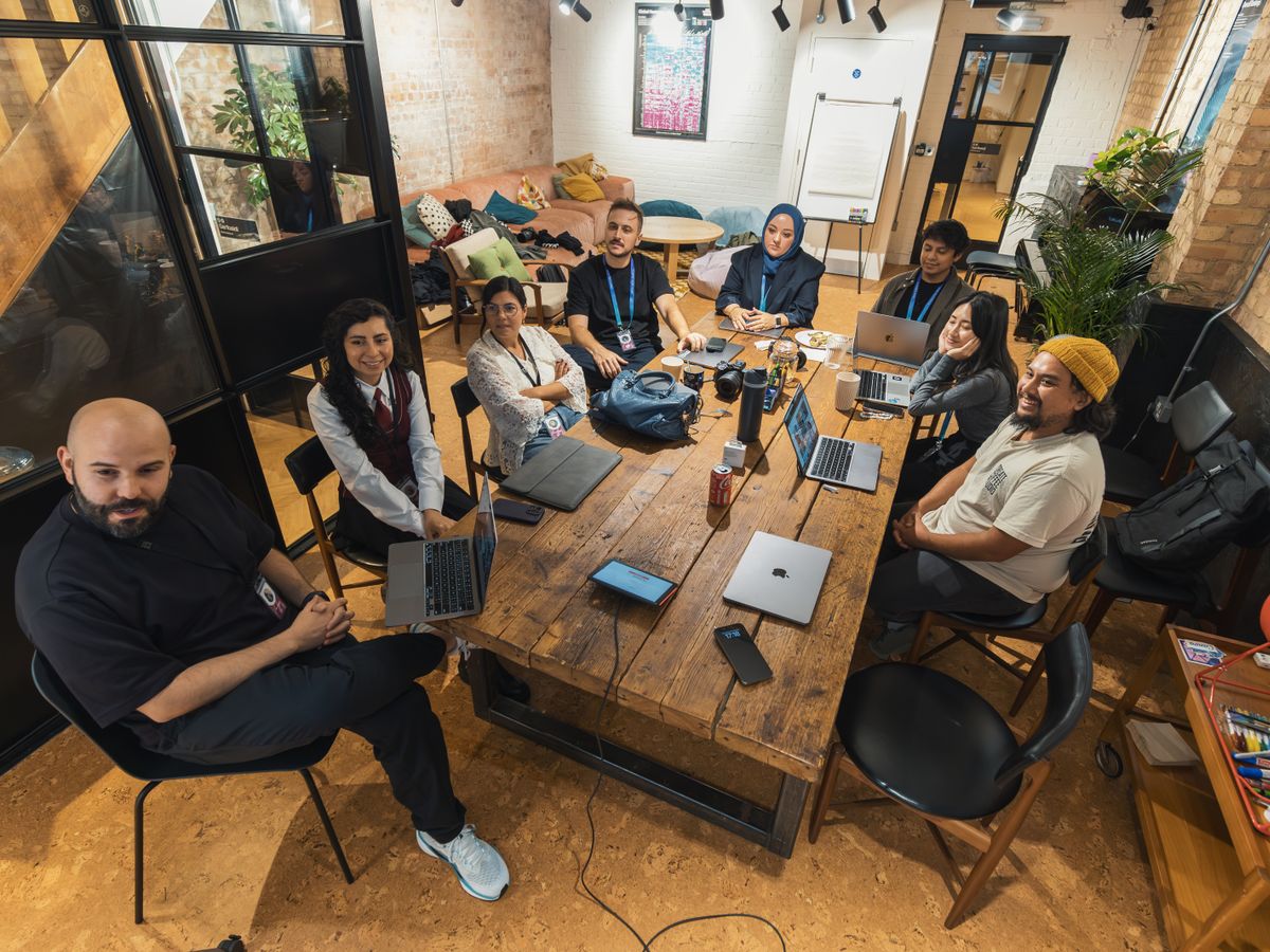 A large mixed team gathered around a shared worktable in an open office