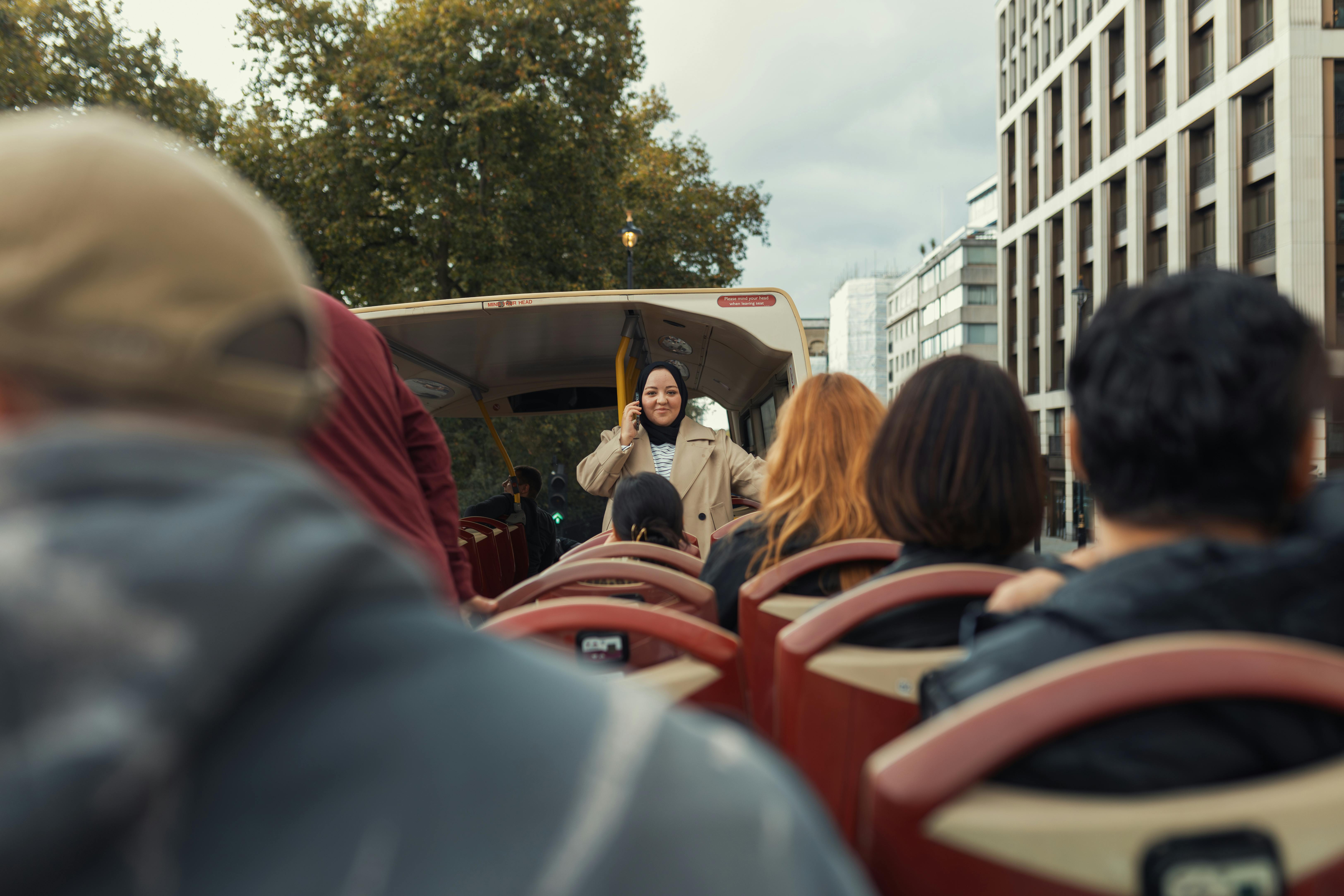 A diverse group of people enjoys a city tour on an open-top bus surrounded by urban architecture and
