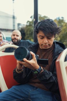 Casual outdoor scene of a photographer reviewing photos on a camera with a blurred background.
