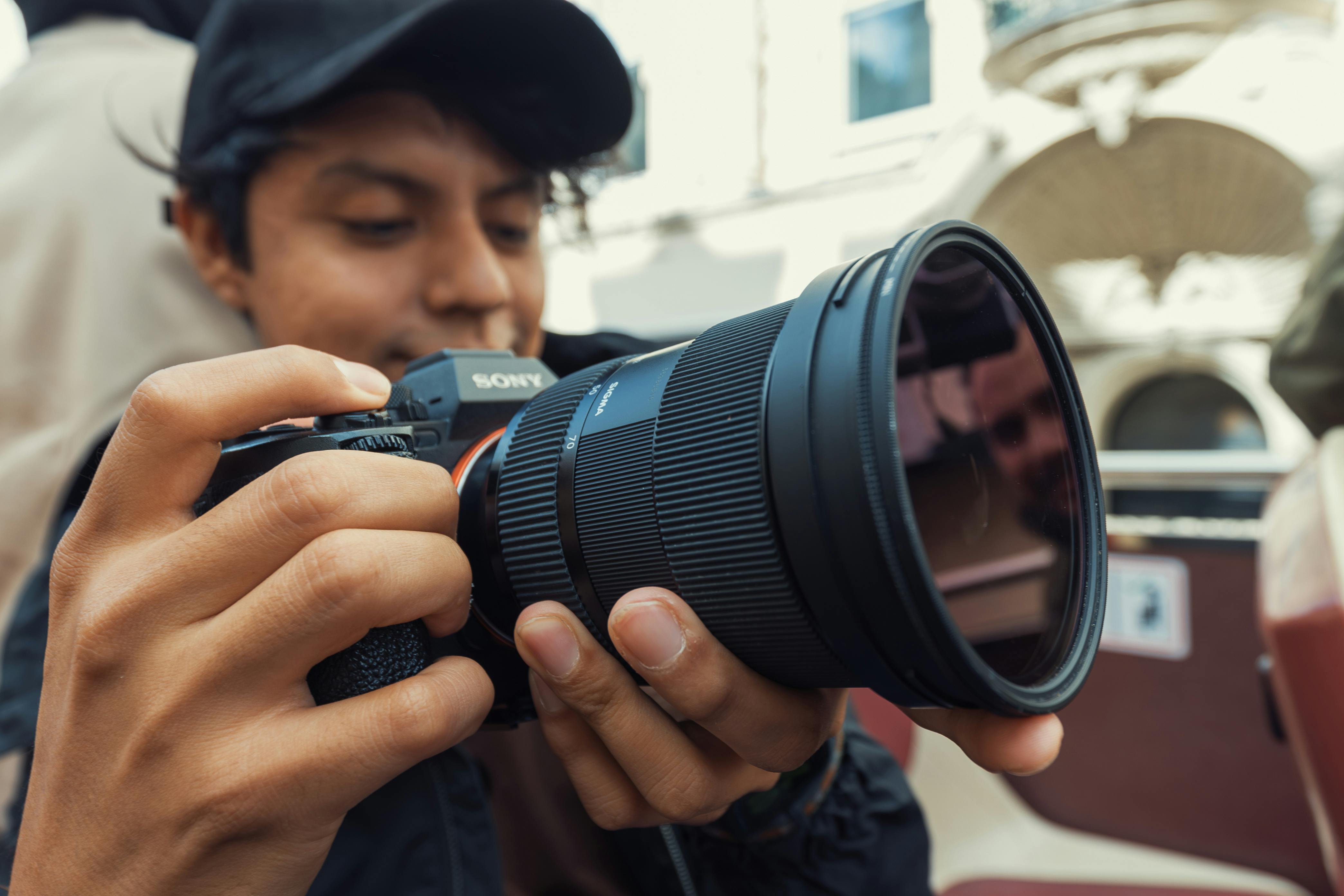 Free Young photographer adjusting camera settings while capturing outdoor scenes. Stock Photo