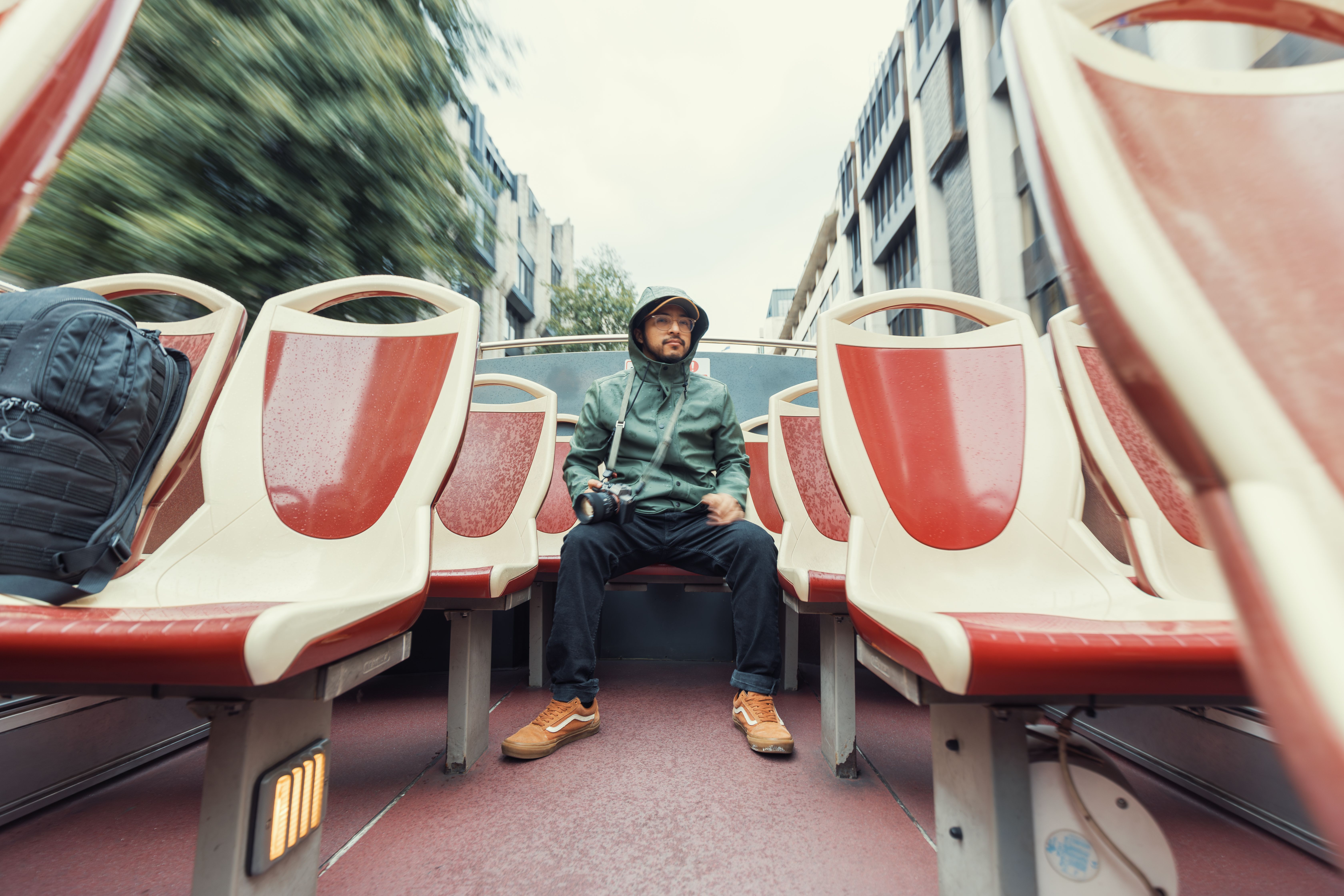 Man in Raincoat on Open-Top Tour Bus · Free Stock Photo